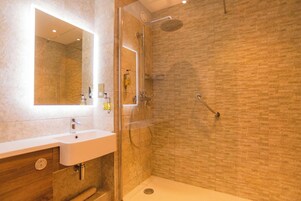 Un baño moderno con ducha de vidrio, un lavabo blanco y un espejo.