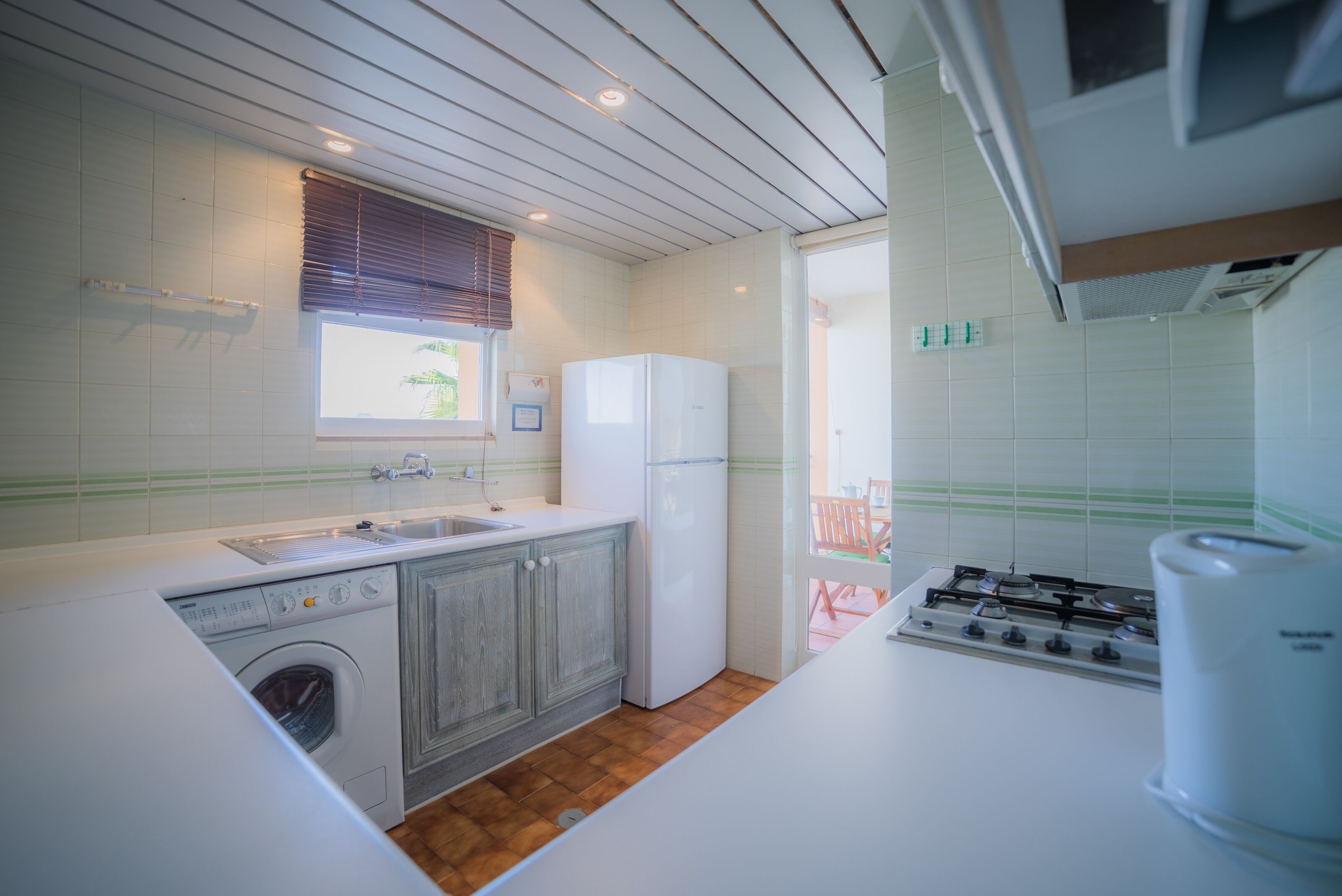 A compact kitchen with a washing machine, a refrigerator, and a gas stove.
