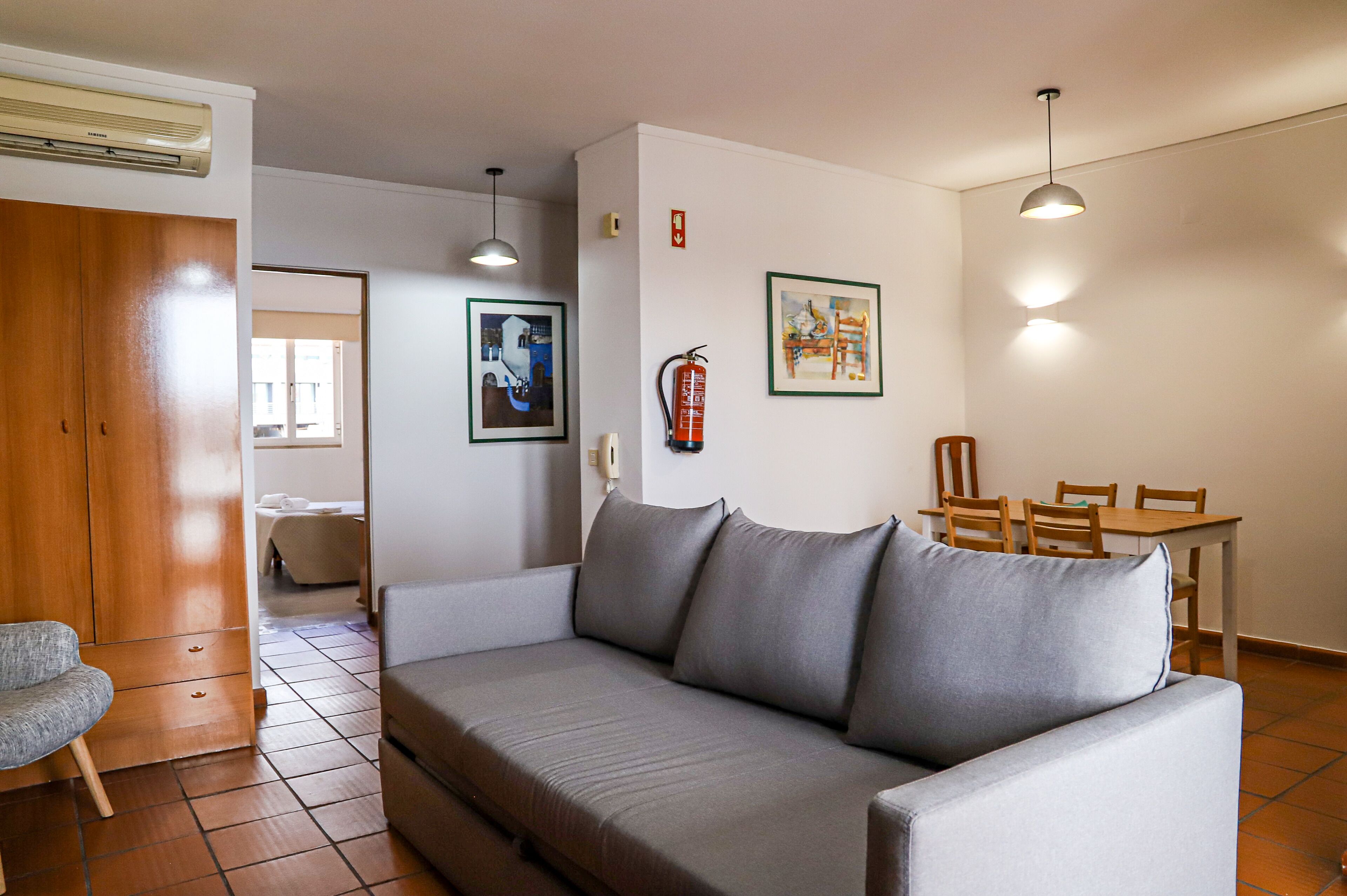 Ein modernes Wohnzimmer mit einem grauen Sofa, Holzmöbeln und Kunstwerken an den Wänden.