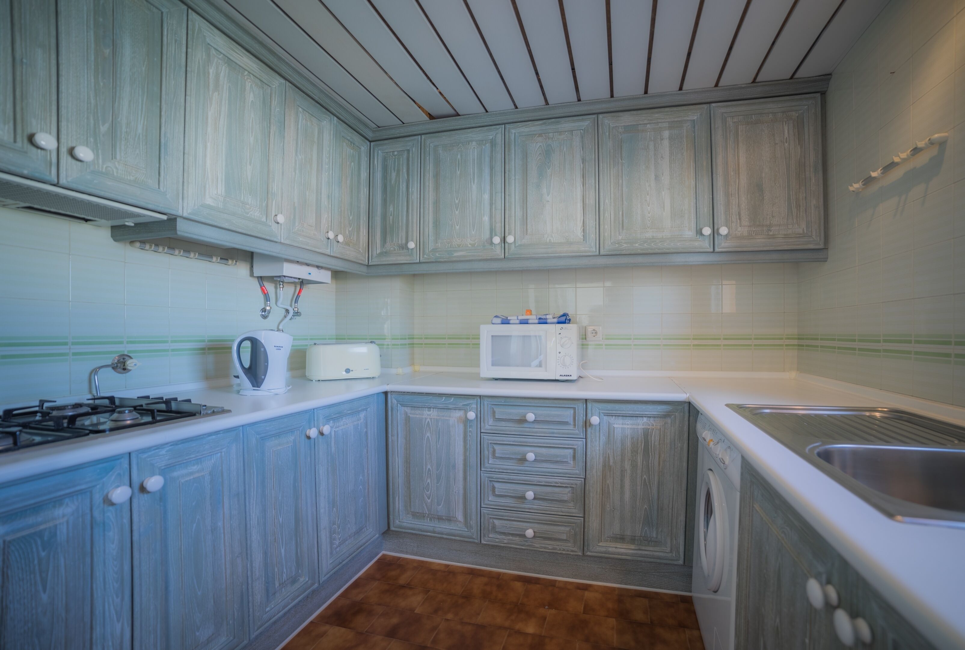 A kitchen with wooden cabinets, a microwave, a toaster, and a sink.