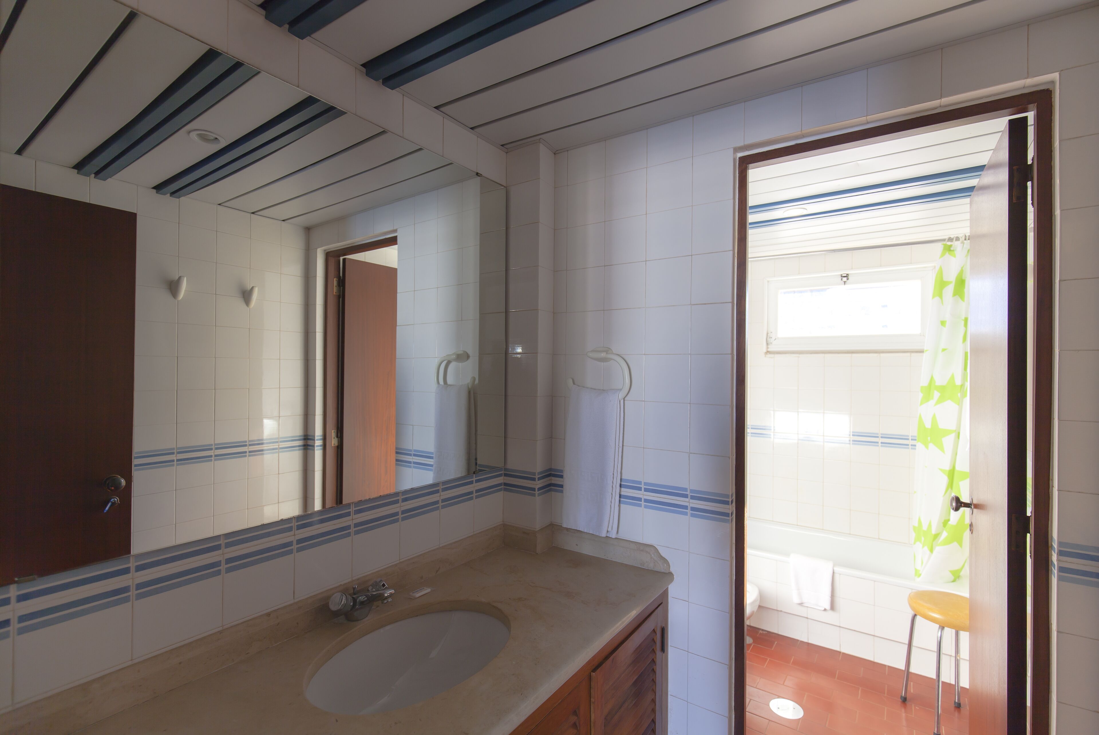 A bathroom with a sink, mirror, and shower area.