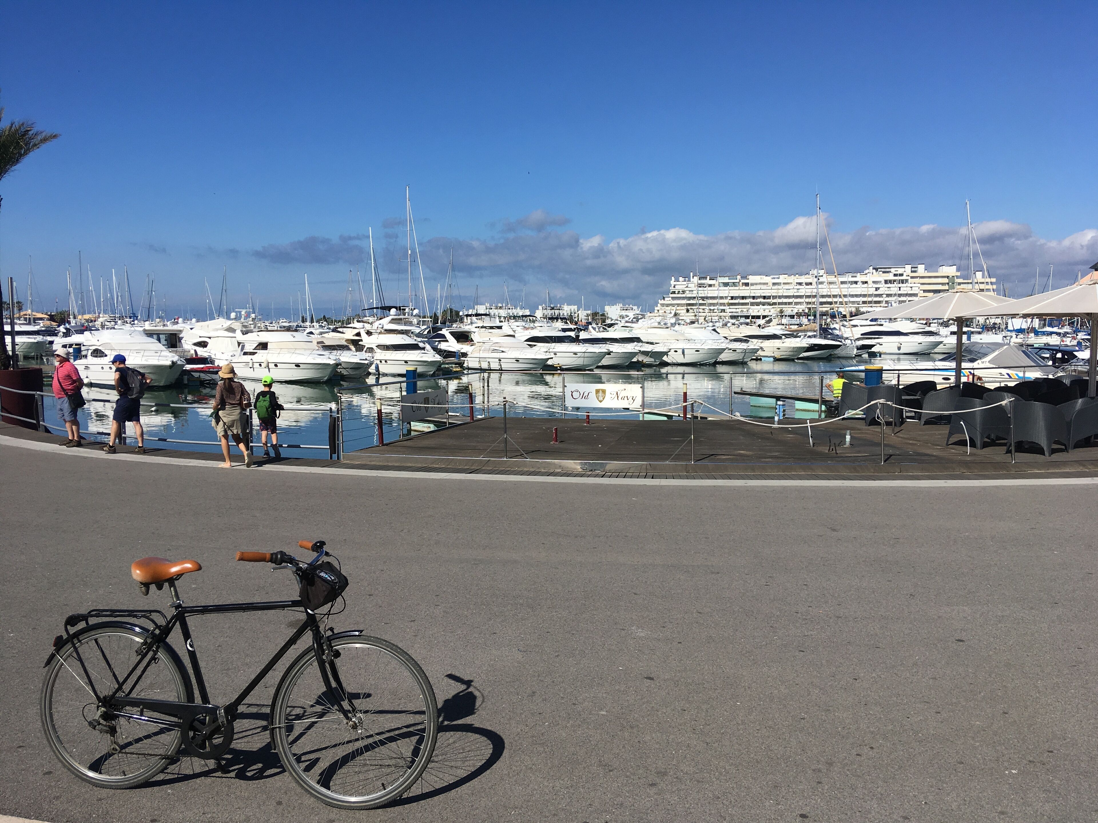 A bicycle parked on a paved area with a marina in the background.