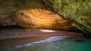 A cave with a large rock formation and a beach area with people and boats. - Marina Plaza - Apartments (Loule)