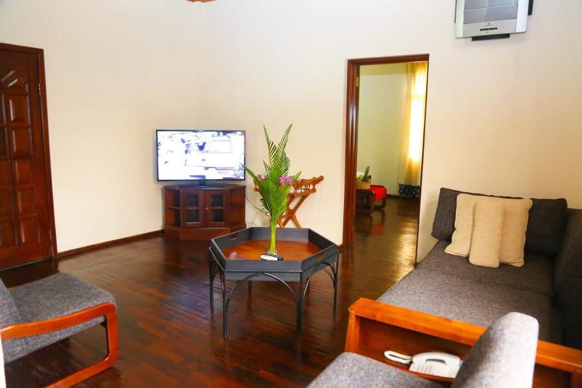 Una sala de estar con un sofá, una mesa de centro, un televisor y piso de madera.