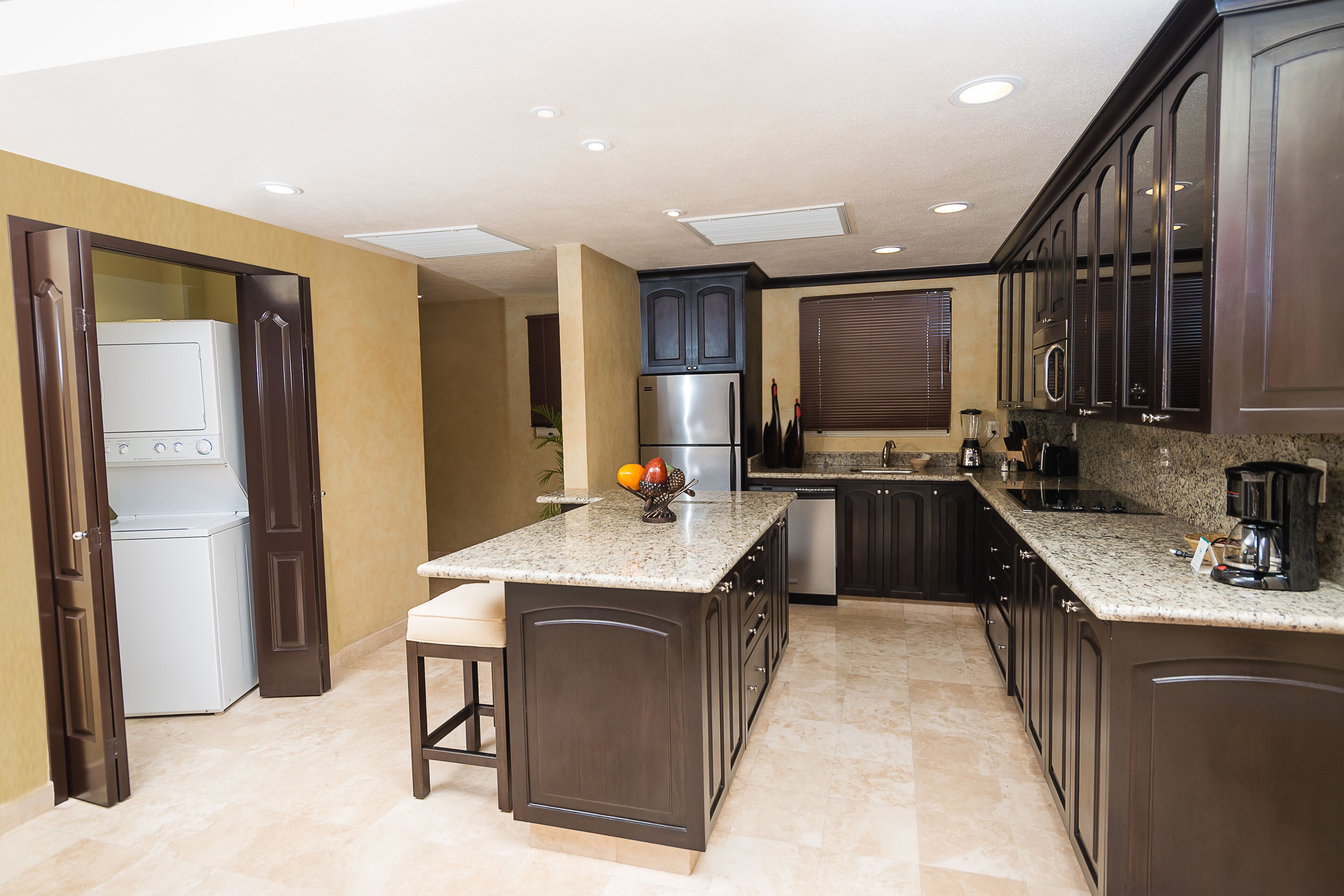 Una cocina moderna con armarios de madera oscura, una isla integrada, electrodomésticos de acero inoxidable y encimera de granito.