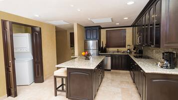 Una cocina moderna con armarios de madera oscura, una isla integrada, electrodomésticos de acero inoxidable y encimera de granito.