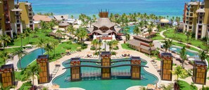 Ein Resort mit mehreren Swimmingpools, Palmen und einem zentralen Geb äude mit einem markanten Dach.