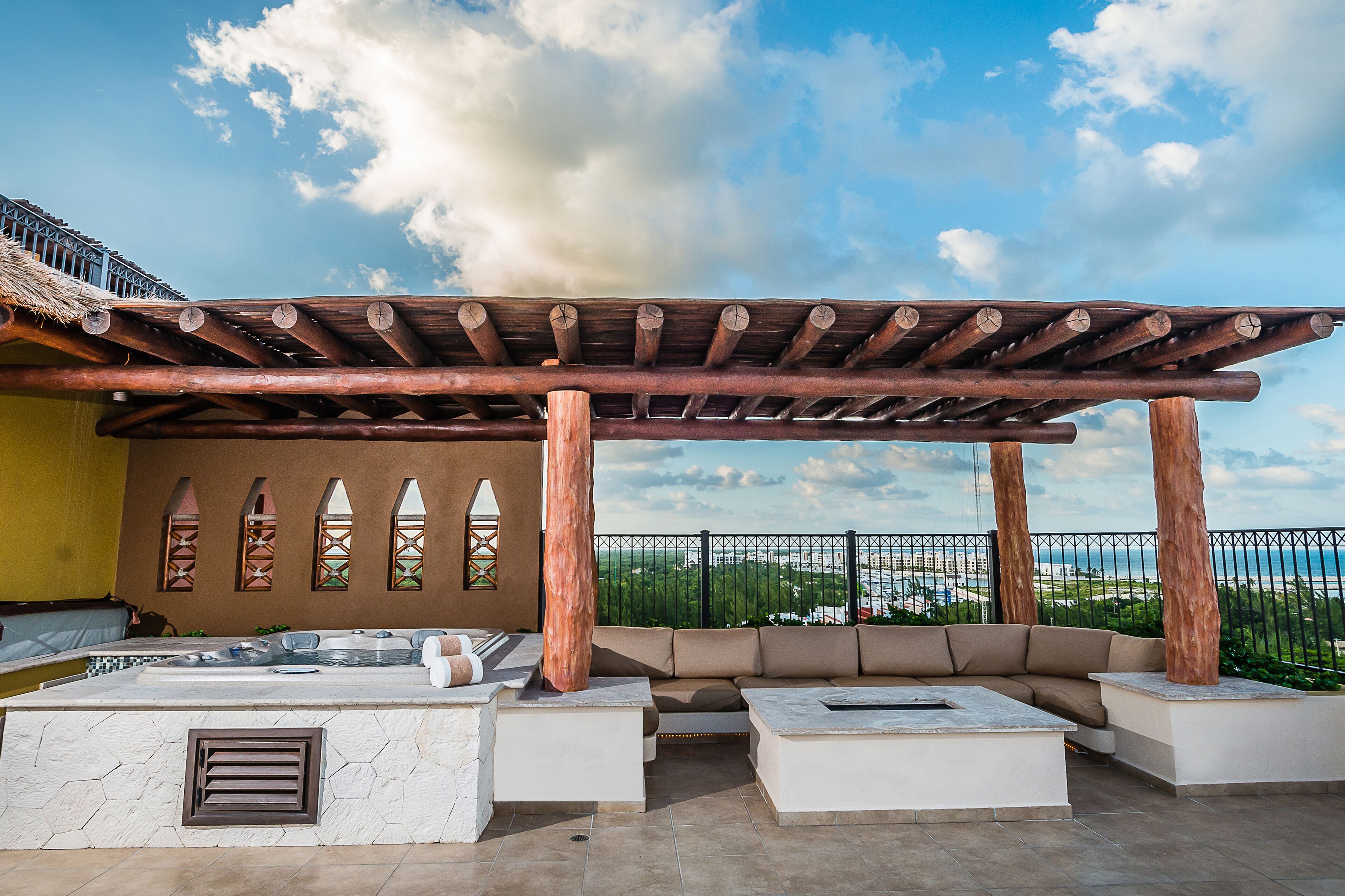 Un patio exterior con una pérgola de madera, zona de estar y vistas de la ciudad.