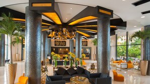 A spacious lobby with a modern design, featuring a central seating area with sofas and armchairs, surrounded by tall columns and large potted plants. - Villa del Palmar Cancun Luxury Beach Resort & Spa (Punta Sam)