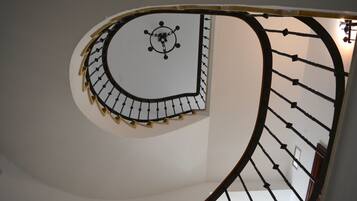 Una escalera de caracol con pared blanca y barandal negro.