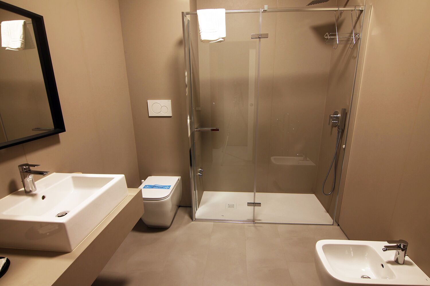 Un baño moderno con ducha de vidrio, lavamanos y un bidé.