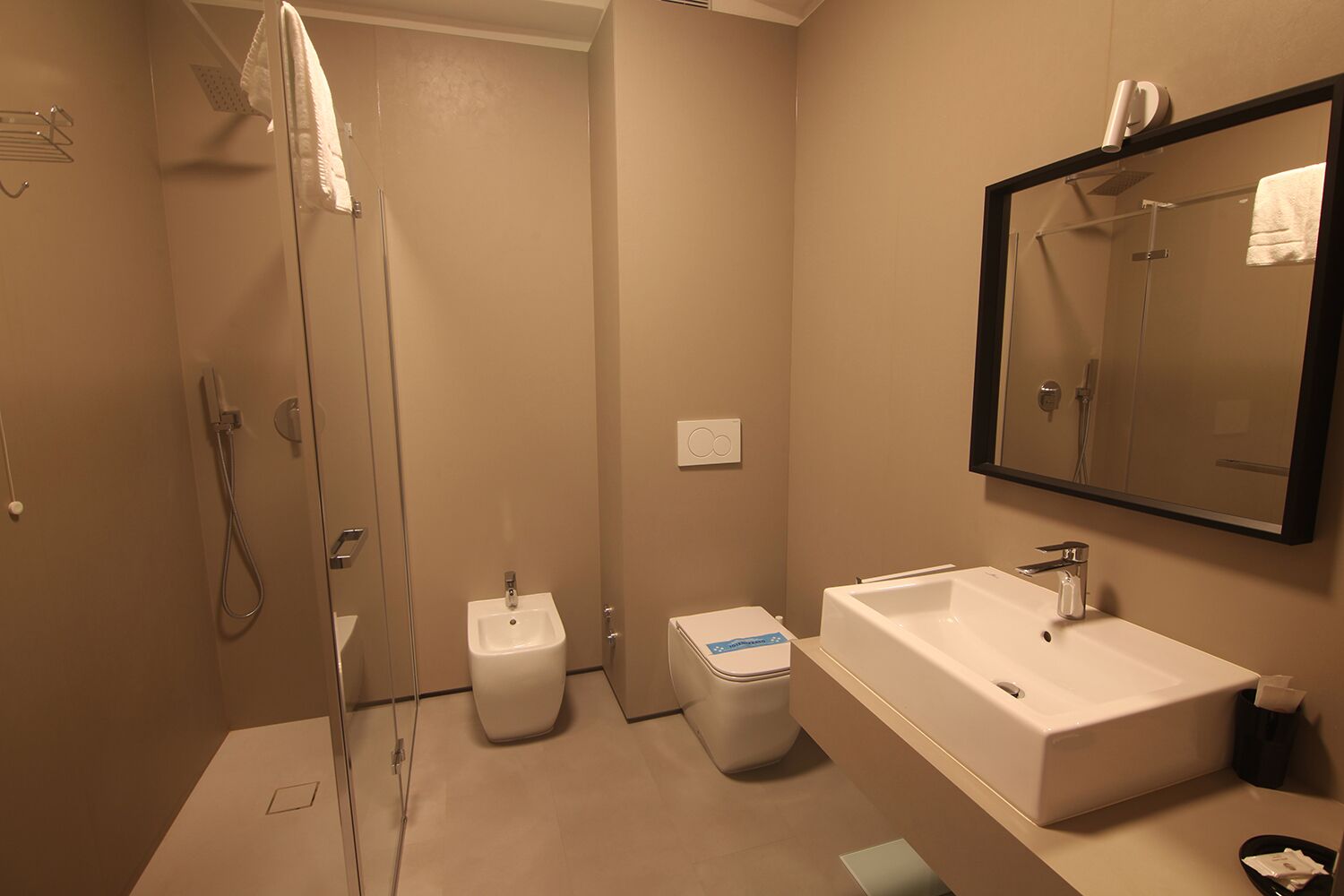 Een moderne badkamer met een douchecabine van glas, een wit wastafelmeubel en een toilet.