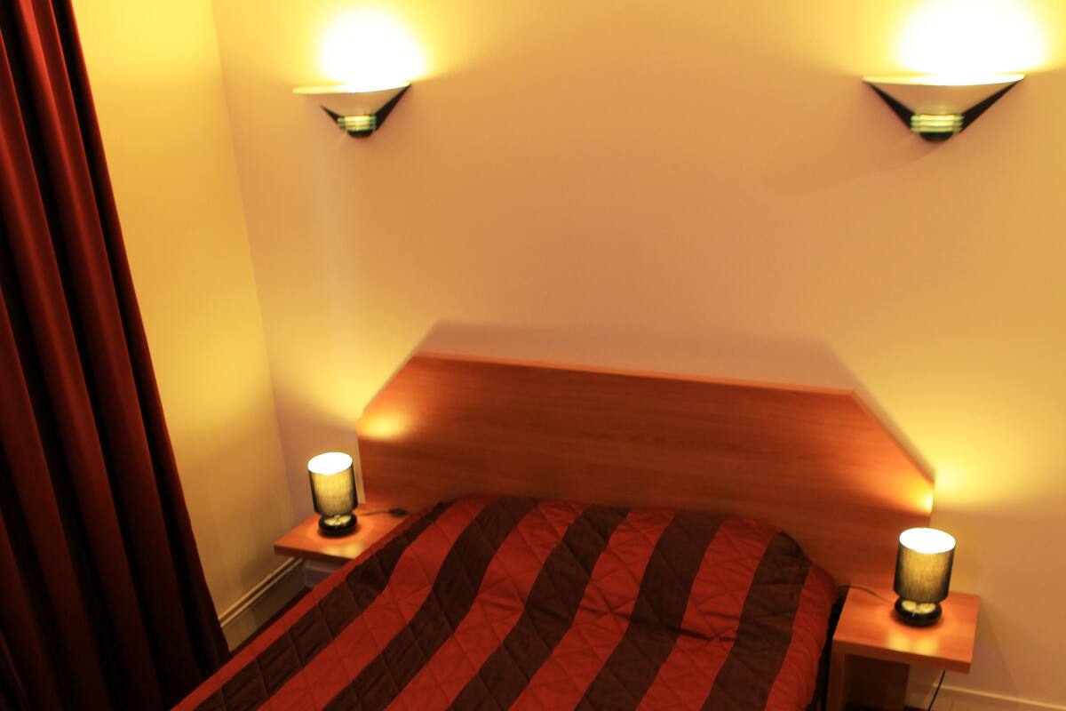 A bed with a striped bedspread, two bedside lamps, and a wooden headboard.