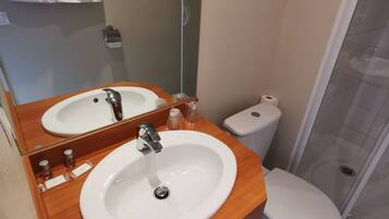 Un baño con dos lavamanos, inodoro y ducha.
