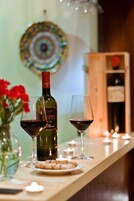 Una zona de bar con una botella de vino, dos copas, un plato de galletas y velas.