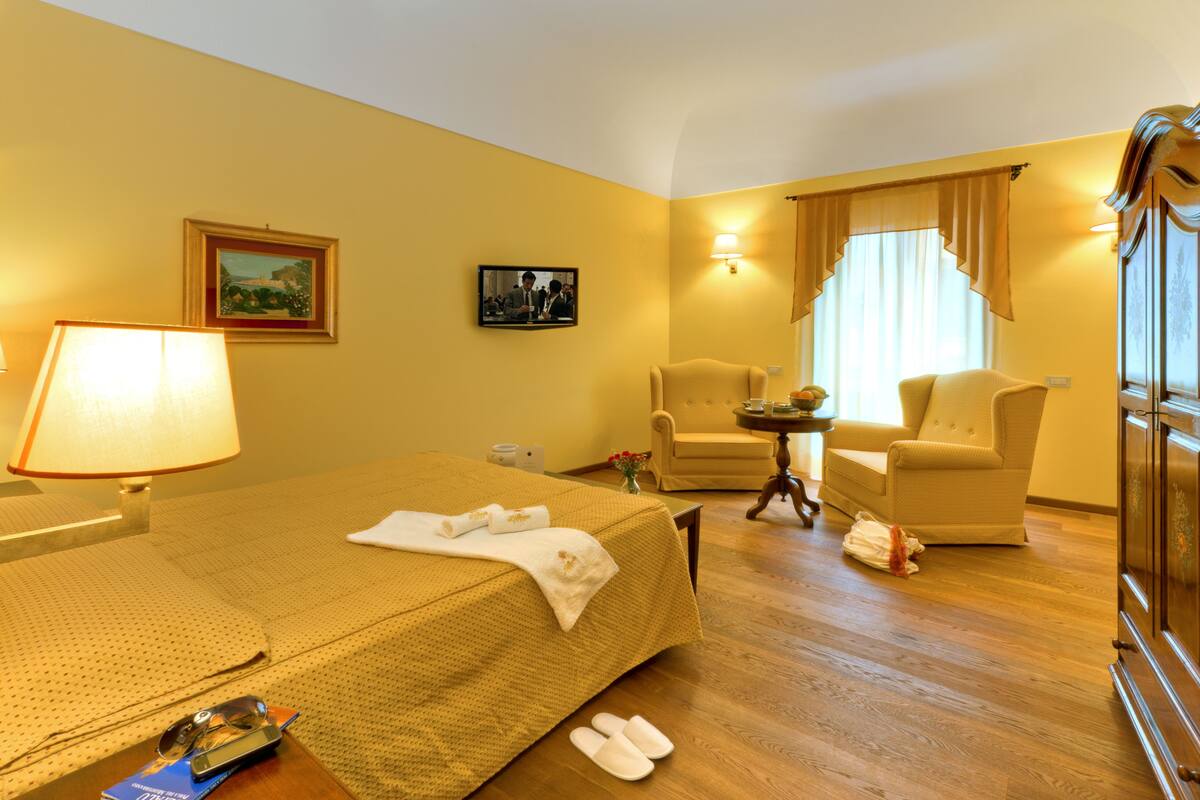 Een hotelkamer met een bed, twee fauteuils, een kleine tafel en een lamp.