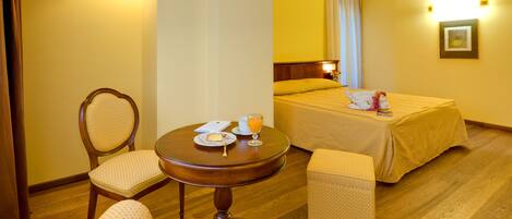 Une chambre d’hôtel comprenant un lit, deux tables de chevet, une table ronde avec des chaises et un petit canapé.