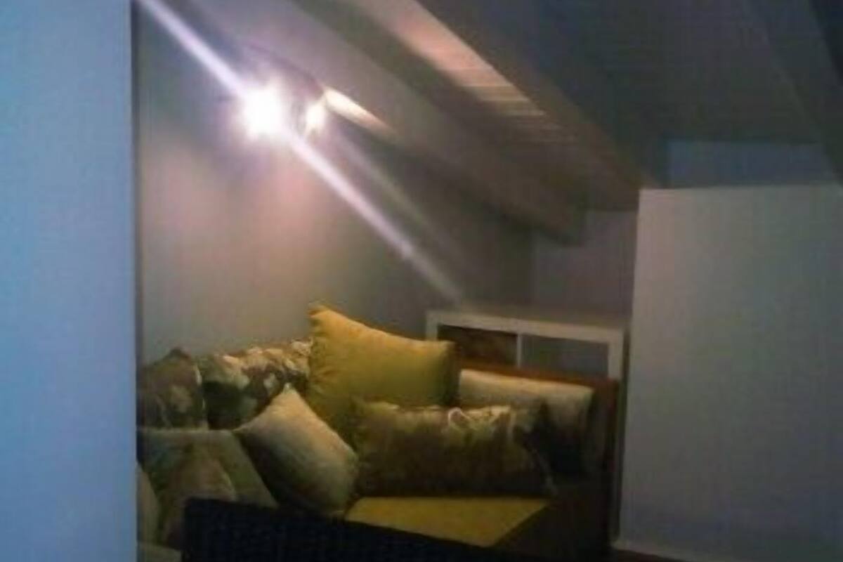A small, dimly lit room with a single bed and a nightstand.