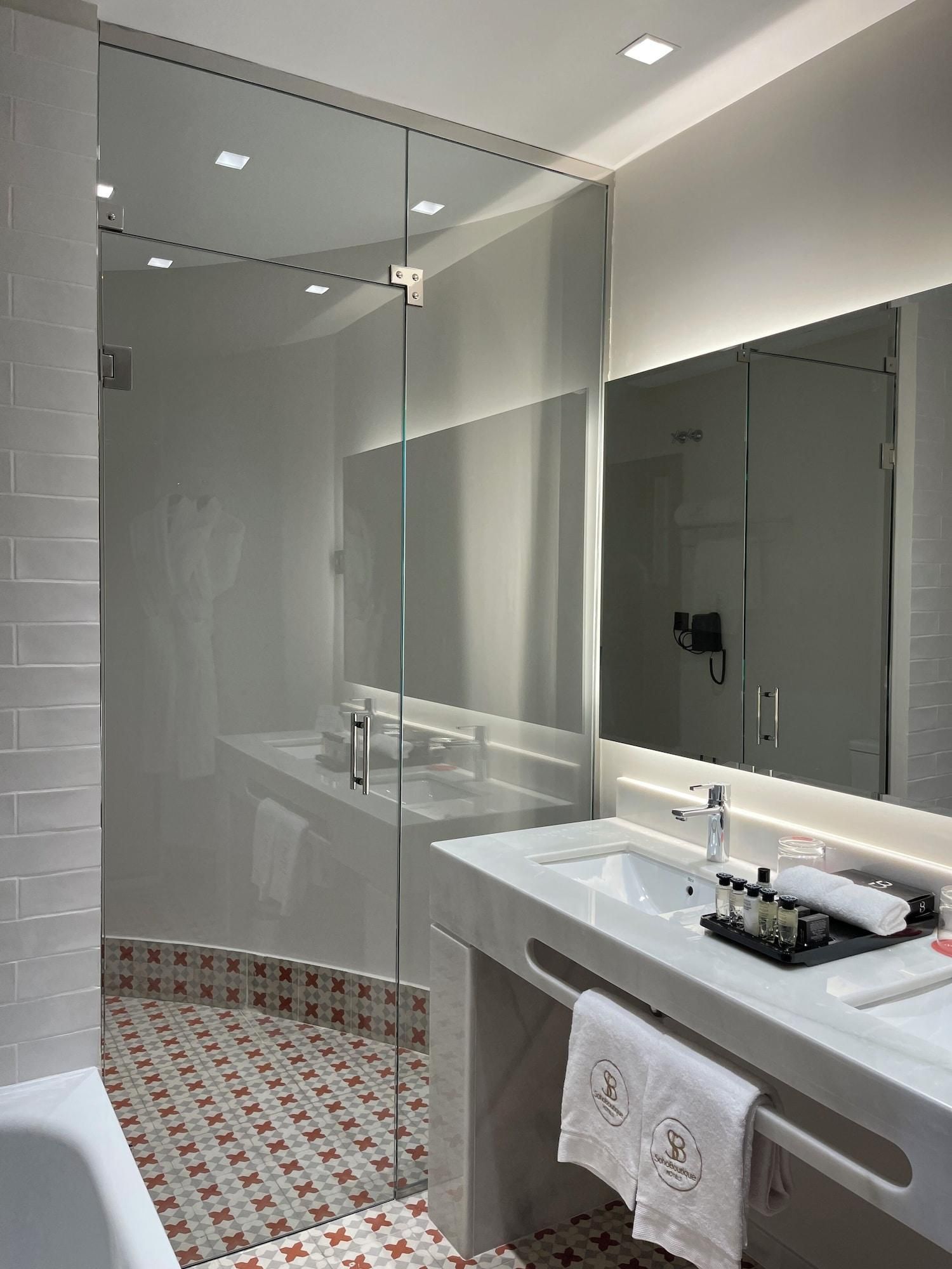 A modern bathroom with a glass shower enclosure, a large mirror, and a vanity with a sink and towel rack.