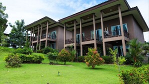 Ein mehrstöckiges Hotel mit Balkonen, umgeben von gepflegten Gärten und viel Grün.