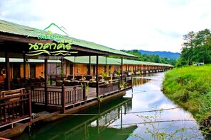 Un restaurant situé au bord de la rivière, doté d’une terrasse et d’une allée couverte.