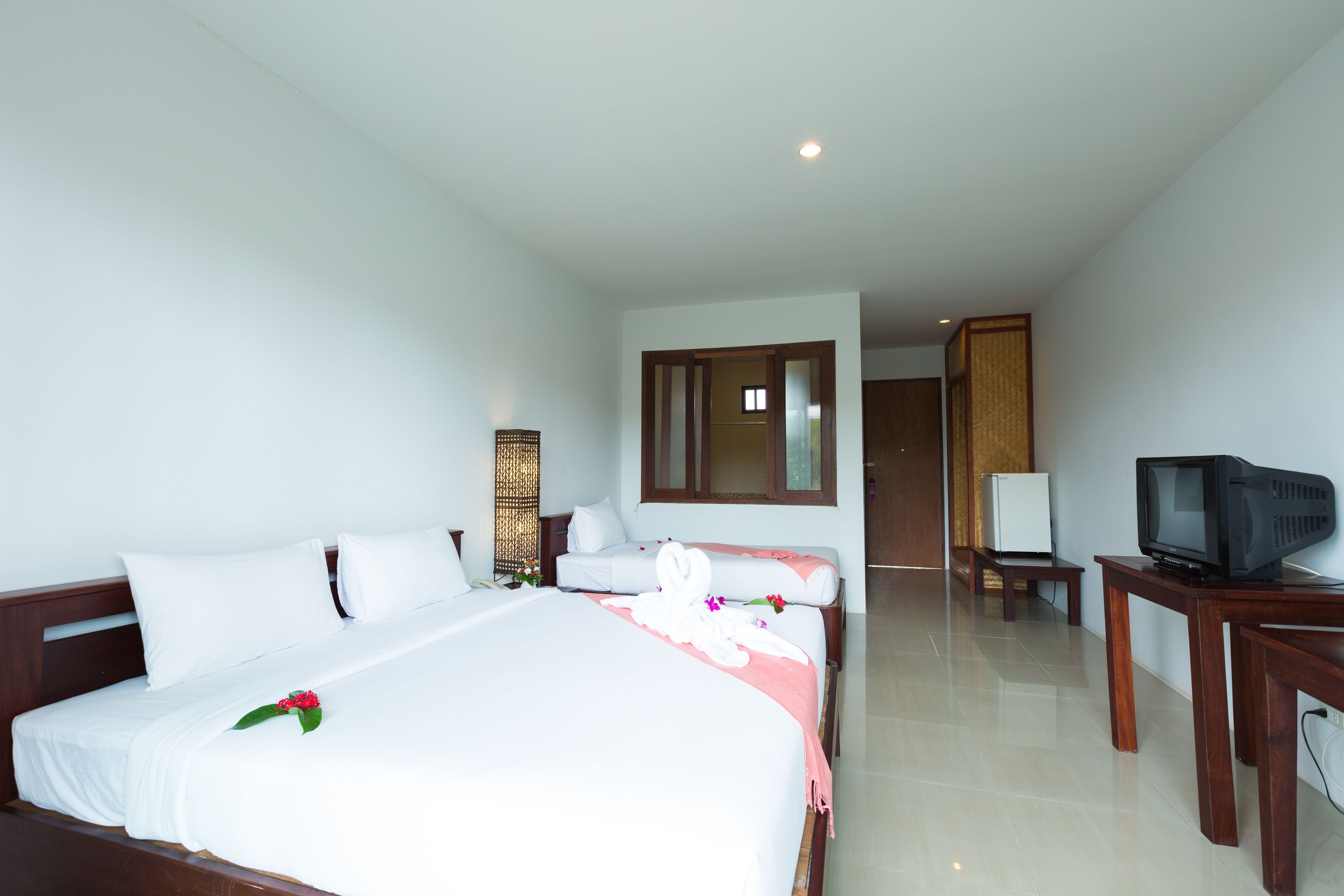Une chambre d’hôtel avec un grand lit, un téléviseur posé sur une table en bois et un petit bureau.