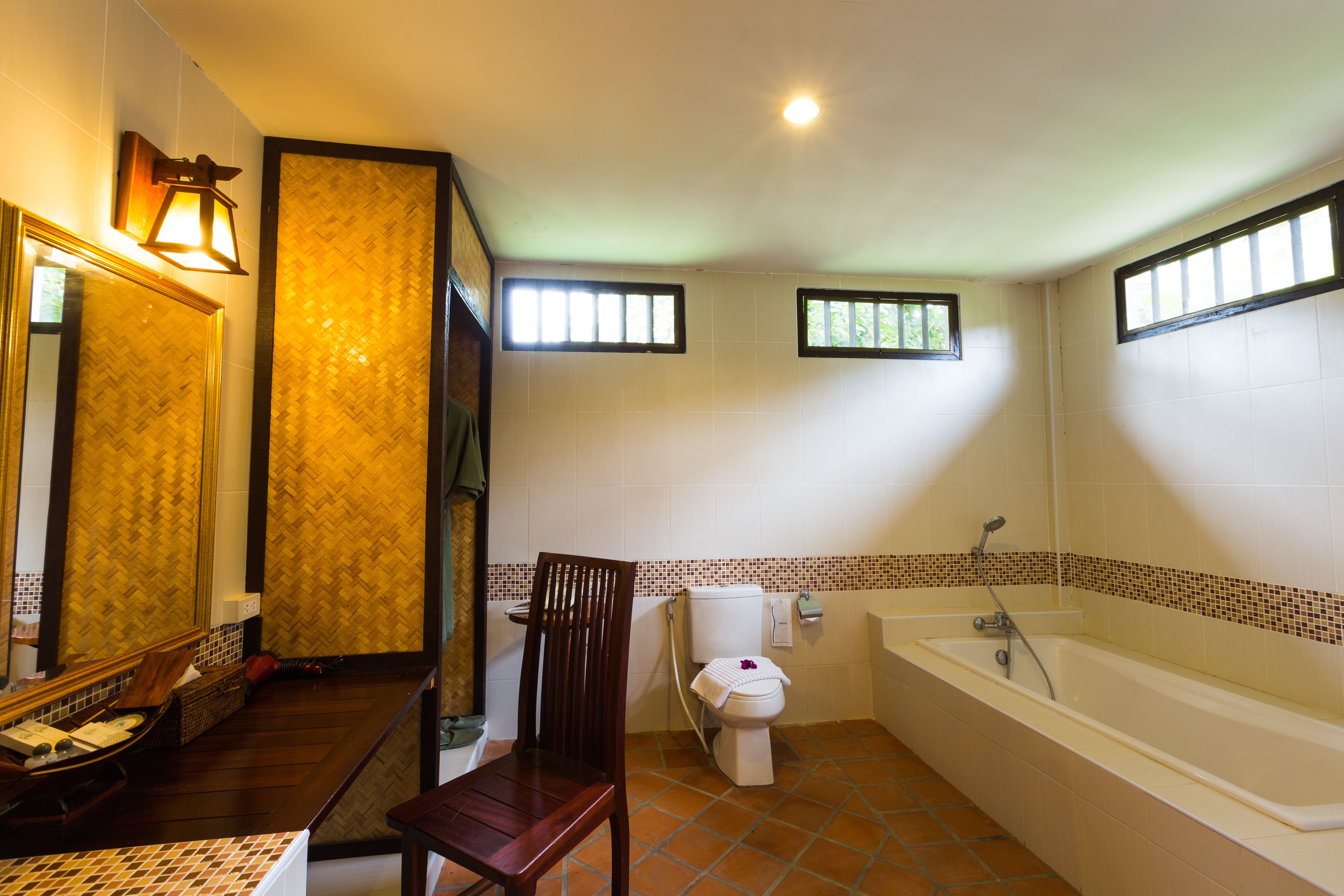 A bathroom with a toilet, bathtub, and a wooden chair.