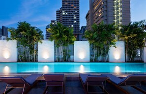 Een buitenzwembad, parasols bij het zwembad en ligstoelen