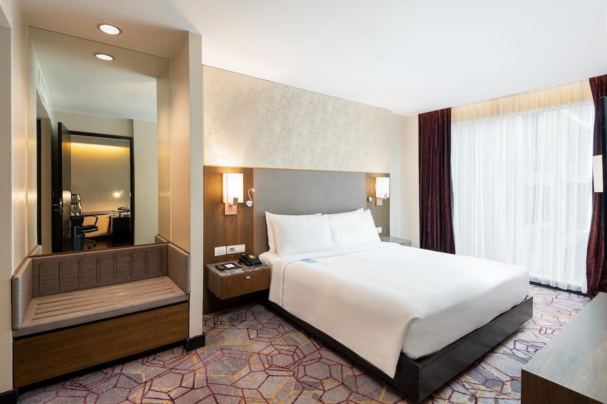 Ein Hotelzimmer mit Bett, Nachttisch, Lampe und Spiegel.