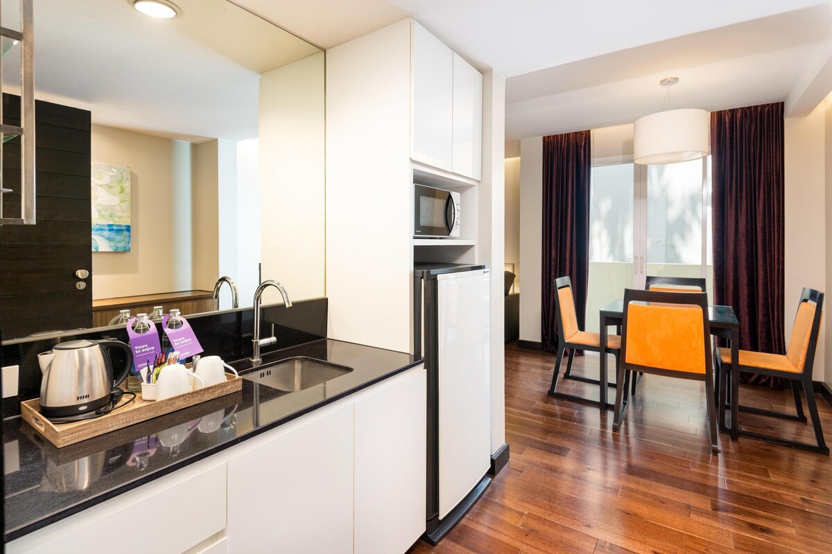 A modern kitchen with a microwave, refrigerator, and sink. There is a dining area with a table and chairs.
