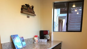 Una cocina con armarios de madera oscura, encimera de granito, cafetera y un modelo decorativo de tren en la pared.