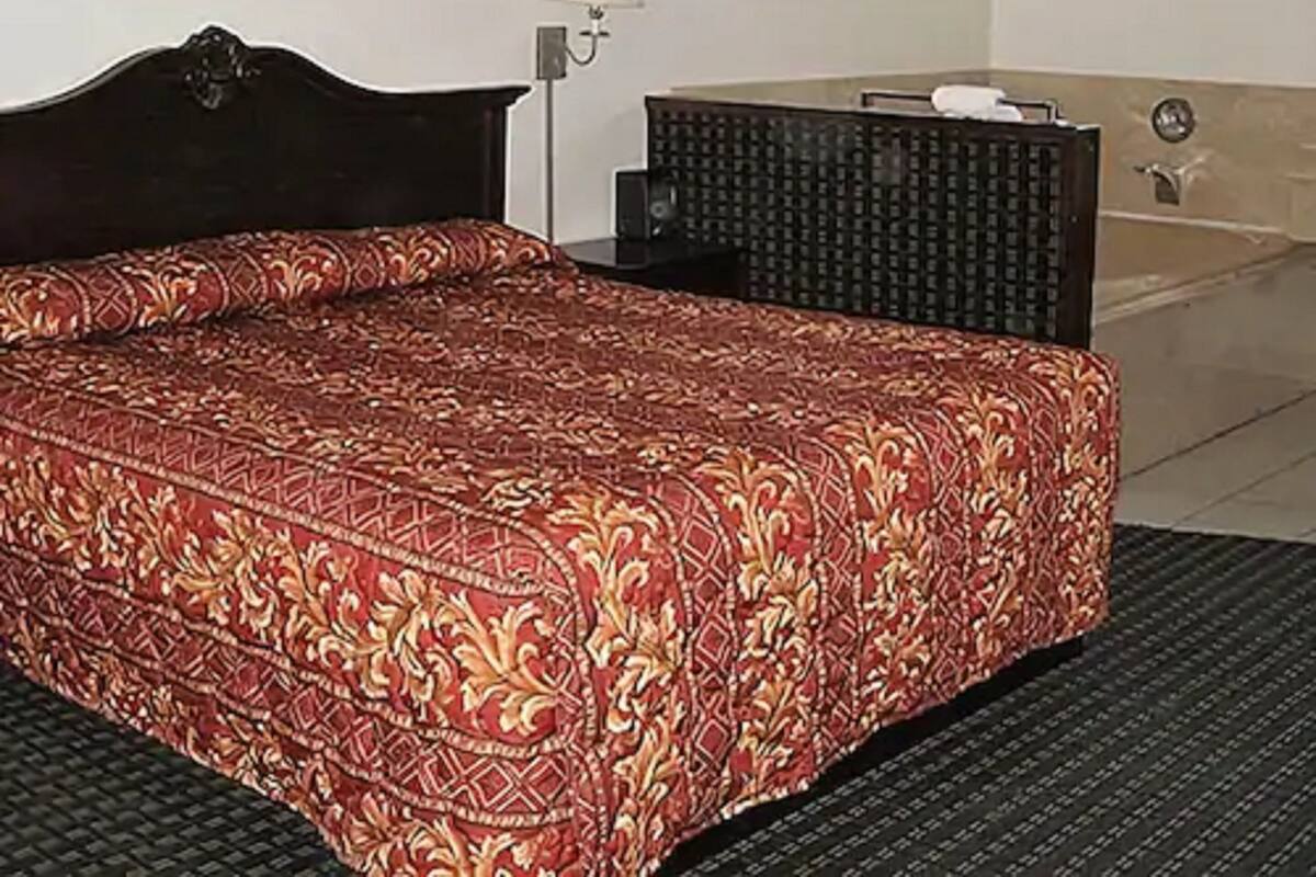 Een hotelkamer met een bed, een lijst met foto aan de muur, een lamp en een badkamergedeelte.