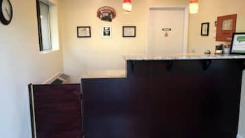 Un área de recepción con mostrador de madera oscura, un reloj, certificados enmarcados y un letrero que dice 'PRIVATE'.