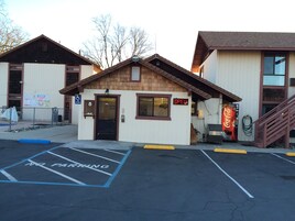 A small building with a Coca-Cola vending machine, a sign indicating 'OPEN', and a parking lot with marked spaces.