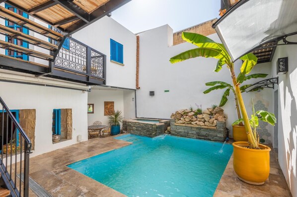 Un patio con piscina, una escalera y una planta grande en maceta.