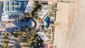 An aerial view of a resort with a tennis court, a pool, and a beach area. - Playa del Sol (Los Barriles)