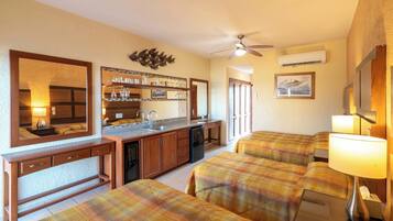 Una habitación de hotel acogedora con kitchenette, una zona de comedor y dos sofás tapizados con estampado escocés.
