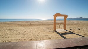 A beach with a wooden structure, sandy terrain, and a clear sky. - Playa del Sol (Los Barriles)