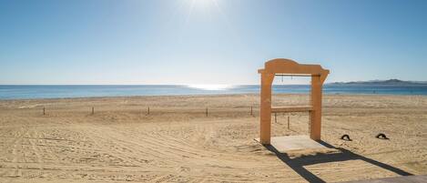 A beach with a wooden structure, sandy terrain, and a clear sky.