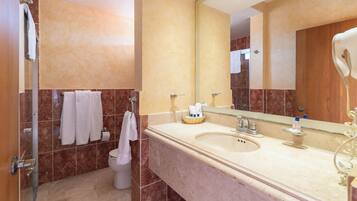 A modern bathroom with a large mirror, a sink, and a shower.