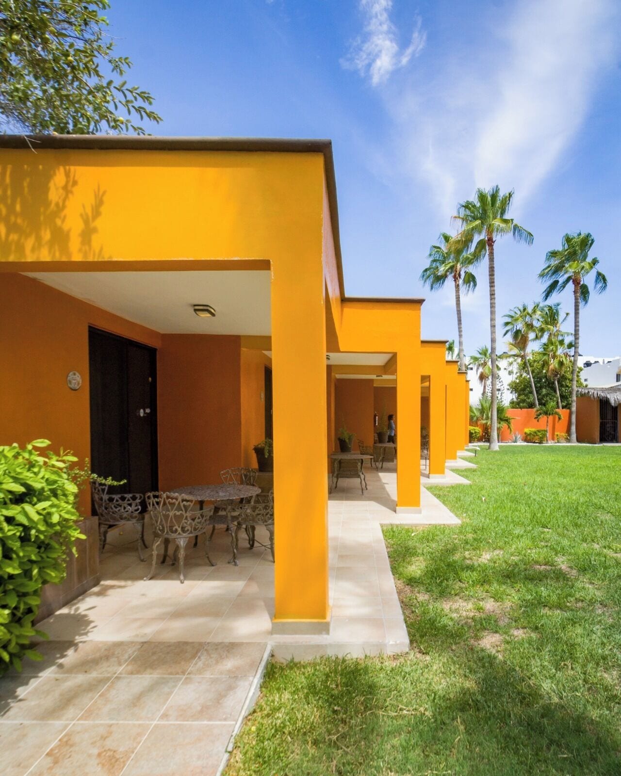A modern building with yellow walls and a covered patio area.