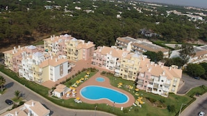 A residential complex with multiple apartment buildings, a central swimming pool, and surrounding greenery. - Eden Village - Apartments (Loulé)