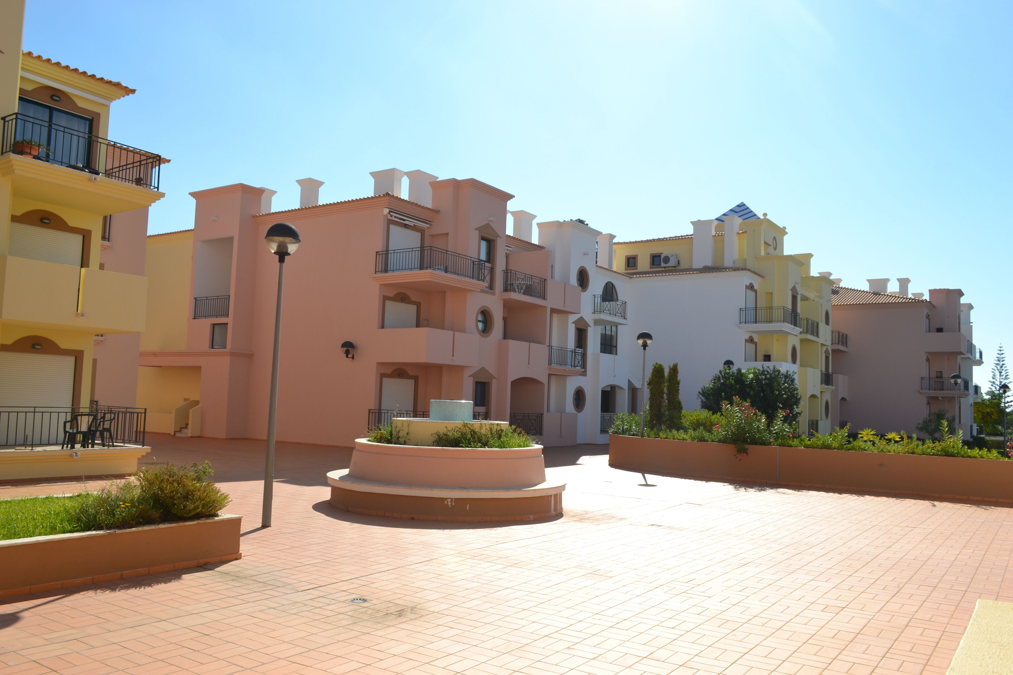 Un quartier résidentiel composé d’immeubles à plusieurs étages, dotés de balcons, et d’une cour dallée agrémentée de jardinières.