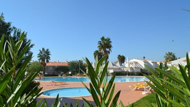 A pool area with lounge chairs and palm trees. - Eden Village - Apartments (Loulé)