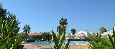 Una piscina al aire libre, sombrillas, sillones reclinables de piscina