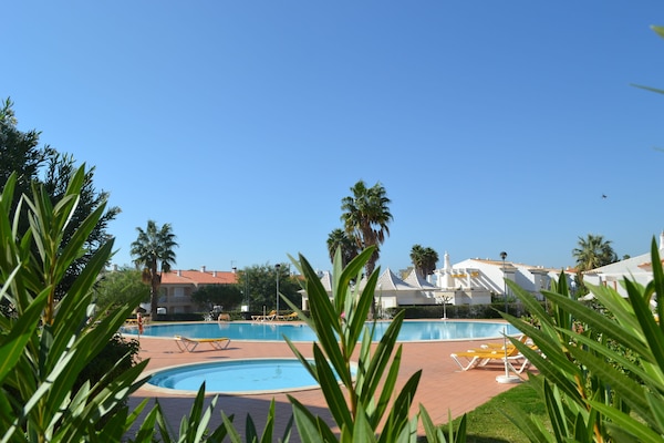Een buitenzwembad, parasols bij het zwembad en ligstoelen