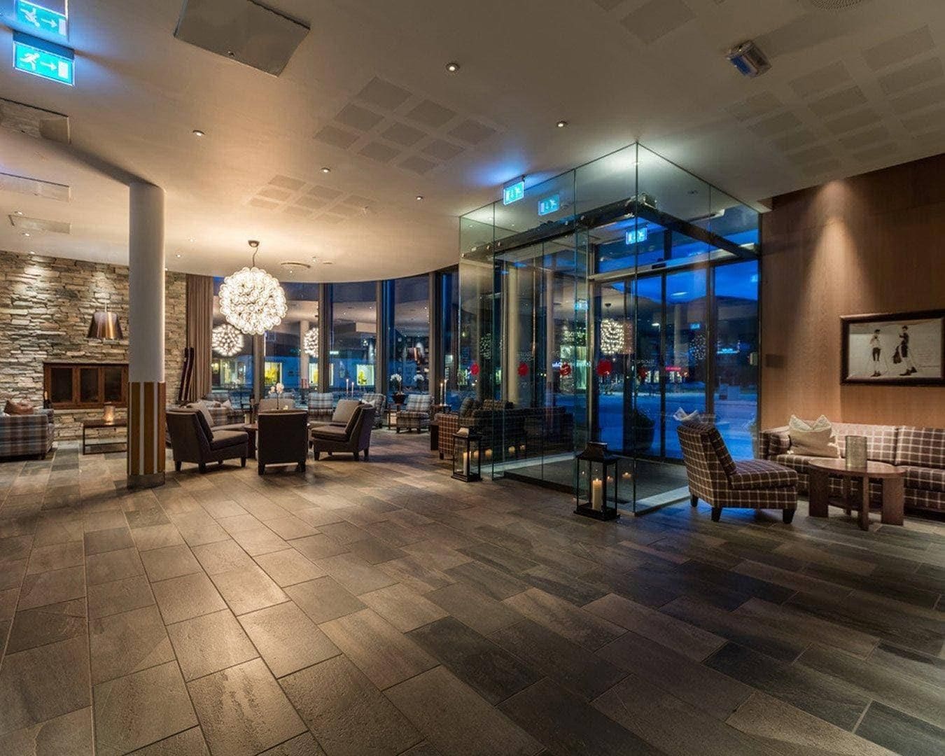 A hotel lobby with a stone wall, seating area, and a glass elevator.