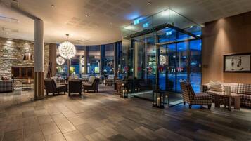 A hotel lobby with a stone wall, seating area, and a glass elevator.