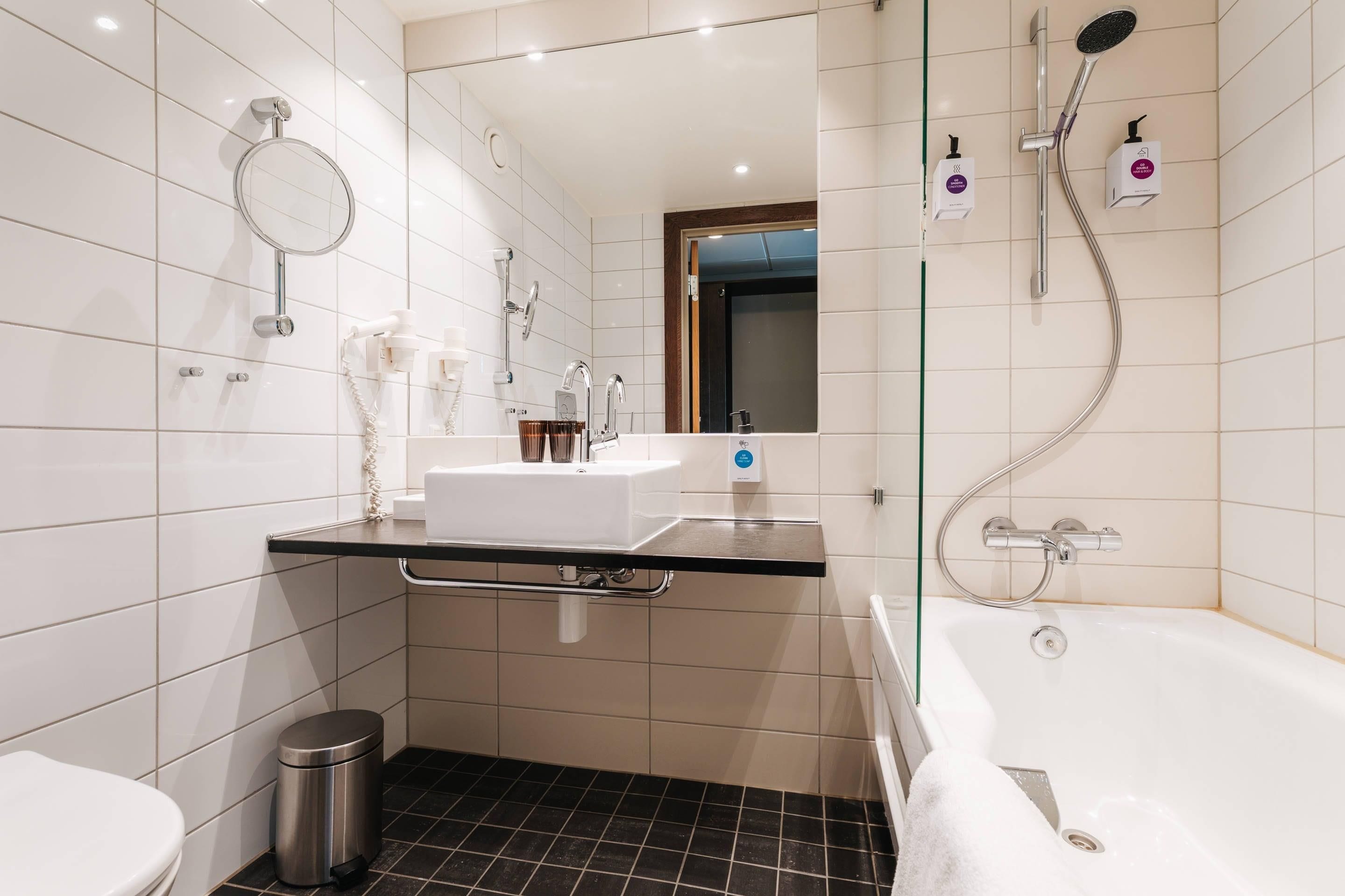 Un baño moderno con una bañera, un lavabo, un espejo y una ducha.