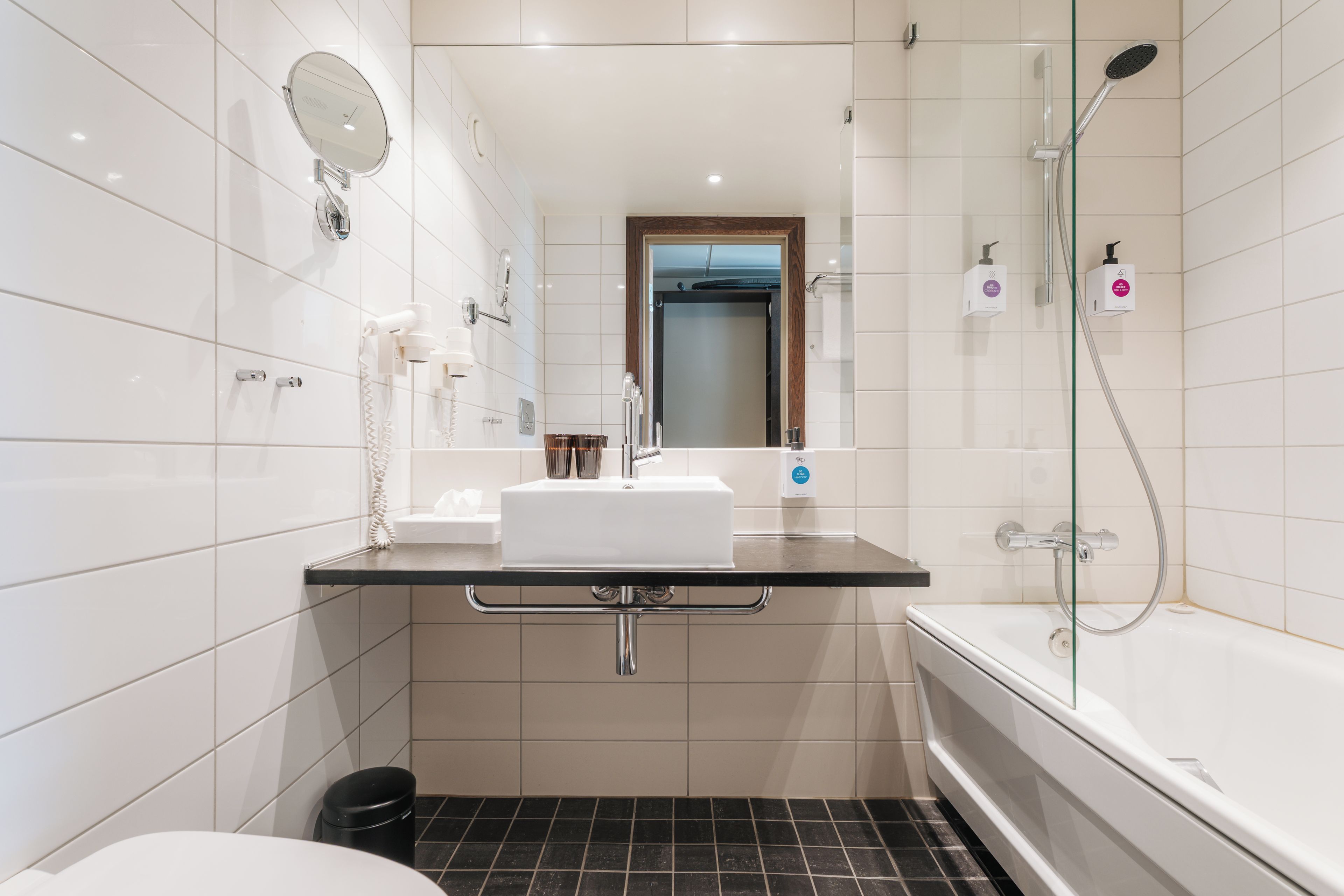 Un bagno moderno con lavandino, specchio e doccia bianchi.